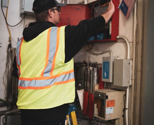 A man in a safety vest working on an electrical panel